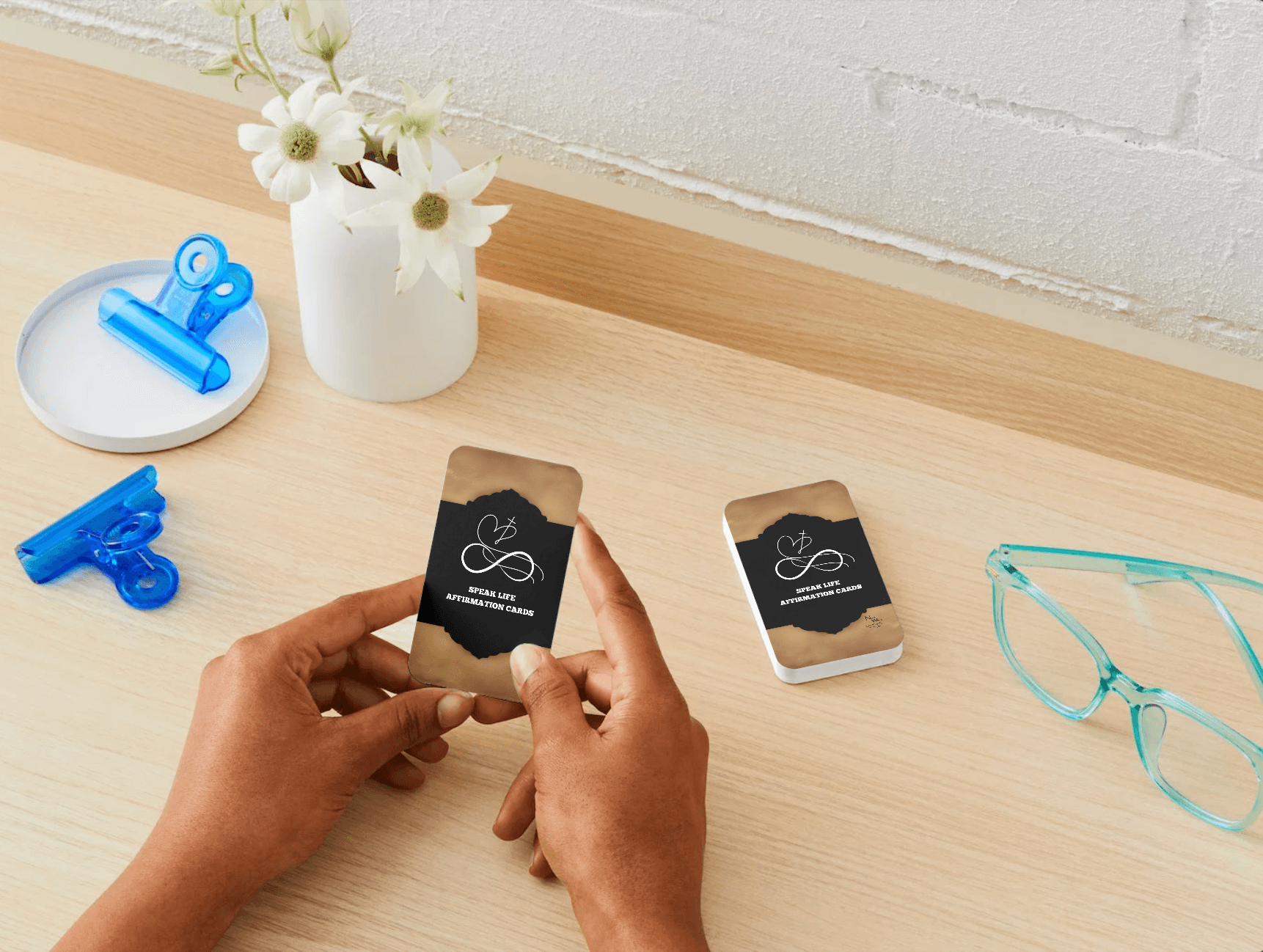 NEW WAVE SPEAK LIFE AFFIRMATION CARDS BUILD YOUR FAITH prayer cards displayed on a wooden desk with a person holding one card and a stack nearby. Ideal for daily Christian inspiration and faith-building routines.